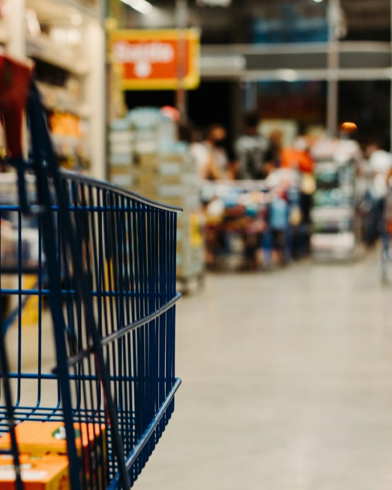 Carrinho de compras em supermercado, remetendo a estratégias para gastar menos