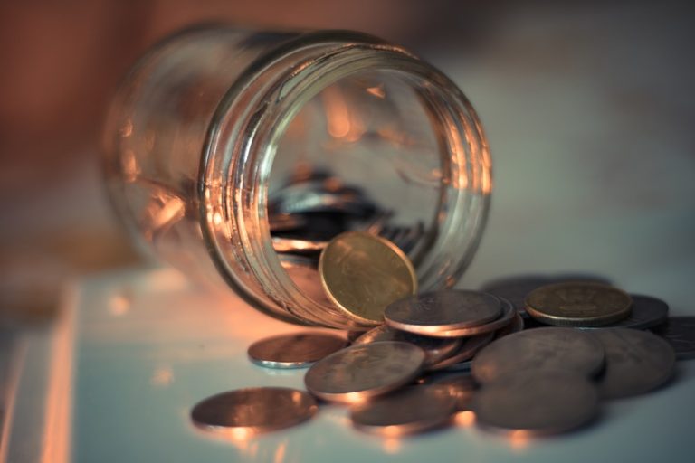 Moedas sendo guardadas em pote, simbolizando a criação de uma reserva de emergência