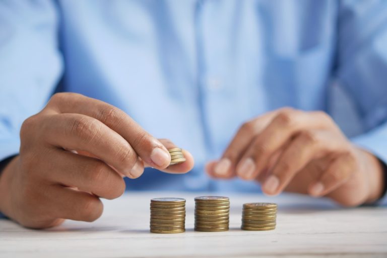 Mão segurando cartão perto de calculadora, representando a escolha entre poupar e investir