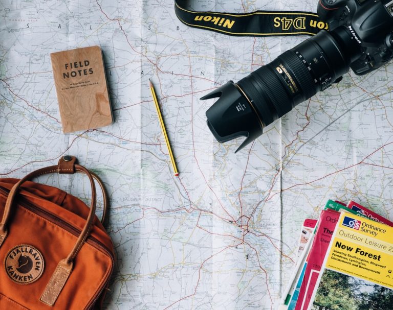 Mapa, lanterna e caderno de anotações para planejar uma viagem sem se endividar